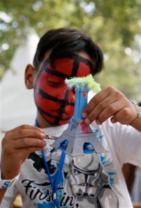 Mohamed from Algeria paints a multicolored model of the Eiffel Tower during the Vacation for Everyone day event at the Eiffel Tower in Paris, France, Wednesday Aug. 19, 2015. The French charity Secours Populaire brought children from dozens of different countries, including those living through war, poverty or natural disasters, to join kids from France for a day of summer fun, allowing even those with limited means to take a vacation at the height of the French holiday season. (AP Photo/Francois Mori)