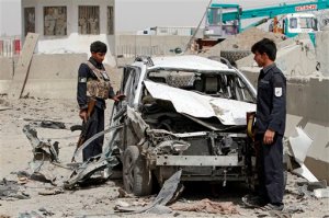 Afghan security forces inspect the site of a suicide car bombing that targeted a police checkpoint in the Daman district, on the outskirts of Kandahar, Afghanistan, Sunday, Sept. 20, 2015. An Afghan official says several people, including two police officers, were wounded in the suicide attack in Afghanistan, while at least 20 other civilians were wounded in separate attacks. (AP Photo/Allauddin Khan)