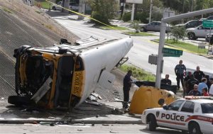 Investigators work around a Houston school bus, left, after it drove off a highway overpass, Tuesday, Sept. 15, 2015, in Houston, killing two students and seriously injuring three other people, police and school officials said. (AP Photo/Pat Sullivan)