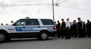 Police officials follow Fox Lake Police Lt. Charles Joseph Gliniewicz's family after a vigil at Lakefront Park to honor him on Wednesday, Sept. 2, 2015, in Fox Lake, Ill. Gliniewicz was shot and killed Tuesday while pursuing a group of suspicious men. Police are searching for a second day to locate three suspects in the killing. (AP Photo/Nam Y. Huh)