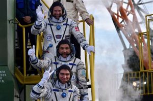 Kazakhstan's cosmonaut Aydyn Aimbetov, center, Russian cosmonaut Sergei Volkov, bottom, and Denmark's astronaut Andreas Mogensen, members of the main crew of the mission to the International Space Station (ISS), gesture near the rocket prior the launch at the Russian leased Baikonur cosmodrome, Kazakhstan, Wednesday, Sept. 2, 2015. (Kirill Kudryavtsev/Pool Photo via AP)