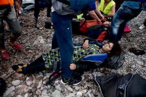 Two women collapse as they arrive with other migrants on the shores of the Greek island of Lesbos after crossing the Aegean Sea from Turkey on an inflatable dinghy, Tuesday, Sept. 22, 2015. More than 260,000 asylum-seekers have arrived in Greece so far this year, most reaching the country's eastern islands on flimsy rafts or boats from the nearby Turkish coast. (AP Photo/Petros Giannakouris)