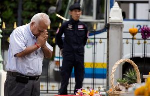 A man prays at the Erawan Shrine, the scene of the Aug. 17 bombing,  as a policeman keeps watch in Bangkok, Wednesday, Sept. 2, 2015. Thai authorities arrested a man they believe is part of a group responsible for a deadly bombing at a shrine in central Bangkok two weeks ago, the prime minister announced Tuesday. (AP Photo/Mark Baker)