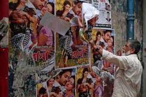 FILE - In this Aug. 25, 2015 file photo, a Bangladeshi movie theatre worker removes posters of a film Rana Plaza in Dhaka, Bangladesh.  The Supreme Court in Bangladesh has lifted a ban on the screening of a movie about a garment worker who was rescued from the rubble 17 days after a five-story factory building collapsed more than two years ago, killing more than 1,000 people. In response to an appeal by the movie's producer, a four-member panel of judges led by Chief Justice Surendra Kumar Sinha decided late Sunday, Sept. 6, 2015,  to stay a previous High Court order that banned the release of the movie for six months. (AP Photo/ A.M. Ahad, File)