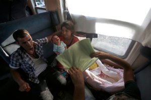 FILE - This is a Wednesday, Aug. 19, 2015, file photo, Amina Asmani, right, with her baby and husband travel on a train taking them towards Serbia, near the southern Macedonian town of Demir Kapija. Almost 39,000 migrants, most of them Syrians, have registered as passing through Macedonia over the past month, double the number from the month before. "We want to go to Germany to find a new life because everything has been destroyed in Syria," said Amina Asmani of Syria, holding her husband's hand and watching her 10-day-old son, who was born on a Greek island during her journey. (AP Photo/Darko Vojinovic, File)