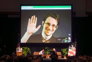 FILE - In this Feb. 14, 2015 file photo, Edward Snowden appears on a live video feed broadcast from Moscow at an event sponsored by ACLU Hawaii in Honolulu. The former National Security Agency worker, who leaked classified documents about government surveillance, started tweeting Tuesday, Sept. 29, 2015. (AP Photo/Marco Garcia, File)