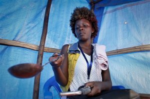 In this photo taken Wednesday, Aug. 19, 2015, Ugandan gold dealer Howart Nasasi heats gold ore in the Mubende district west of the capital Kampala, in Uganda. The gold rush is on in a big way in the Ugandan district of Mubende, with tens of thousands of people making their livelihood from it. (AP Photo/Stephen Wandera)