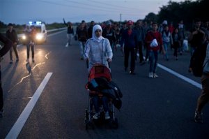 A woman pushes a stroller as she walks on the highway close to Roszke, Hungary, Monday, Sept. 7, 2015. Several hundred Arabs, Asians and Africans tired of waiting for buses broke through Hungarian police lines near the Serbian border Monday and marched north on the main highway towards Budapest as authorities once again demonstrated an inability to control the human tide passing through Hungary. (AP Photo/Marko Drobnjakovic)