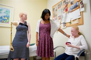 Elissa Montanti, founder and director of the Global Medical Relief Fund, center, places a hand on Pendo Sengerema Noni, right, as Kabula Nkarango Masanja, left, looks on during a prosthetic limb fitting, Tuesday, Aug. 25, 2015, at Shriners Hospital for Children in Philadelphia. Pendo and Kabula along with three other children from Tanzania with the hereditary condition of albinism are in the U.S. to receive free surgery and prostheses at the hospital. The children were attacked and dismembered in the belief that their body parts will bring wealth. (AP Photo/Matt Rourke)