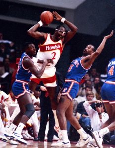 FILE - In this Dec. 28, 1988, file photo, Atlanta Hawks' Moses Malone, center, is double-teamed by New York Knicks' Gerald Wilkins, left, and Eddie Wilkins during an NBA basketball game, in Atlanta. Malone, a three-time NBA MVP and one of basketball's most ferocious rebounders, died Sunday, Sept. 13, 2015, the Philadelphia 76ers said Sunday. He was 60. (AP Photo/File)
