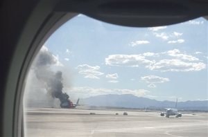 In this photo taken from the view of a plane window, smoke billows out from a plane that caught fire at McCarren International Airport, Tuesday, Sept. 8, 2015, in Las Vegas. An engine on the British Airways plane caught fire before takeoff, forcing passengers to escape on emergency slides. (Eric Hays via AP) MANDATORY CREDIT