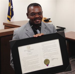 Henry McCollum holds a framed copy of his pardon before a hearing on compensation by the state for his wrongful conviction on Sept. 2, 2015 in Raleigh, N.C. McCollum was the state's longest serving death row inmate when he was released in 2014 after three decades in prison after being wrongfully convicted in a girl's death. (AP Photo/Jonathan Drew)