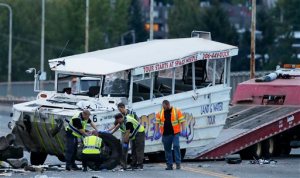 Seattle Police officers photograph the front tire and wheel of a "Ride the Ducks" tourist vehicle before the bus is loaded onto a flatbed tow truck Thursday, Sept. 24, 2015, after it was involved in a fatal crash with a charter passenger bus earlier in the day in Seattle. (AP Photo/Ted S. Warren)