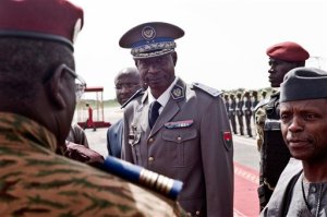 Burkina Faso coup leader Gen. Gilbert Diendere, center, greets people at the airport during the arrival of Niger's President Mahamadou Issoufou for talks in Ouagadougou, Burkina Faso, Wednesday, Sept. 23, 2015. Burkina Faso's interim president declared Wednesday he is once again in charge of the country a week after a military general and his supporters overthrew him and his transitional government. Interim President Michel Kafando had been arrested by members of the presidential guard a week ago, and later sought refuge at the residence of the French ambassador. (AP Photo)