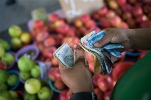 In this Sept. 24,2015 photo, a fruit vendor counts his Real bills at a street market in Rio de Janeiro, Brazil. Now, Brazilians are suddenly confronting rapidly rising prices on everything from cosmetics to cell phones to medicine to that most basic of product that's on virtually all Brazilian tables at breakfast, what locals call "French" bread, crusty little mini loaves that are purchased on a daily basis and are now more expensive as Brazil imports over 60 percent of the wheat it consumes. (AP Photo/Felipe Dana)