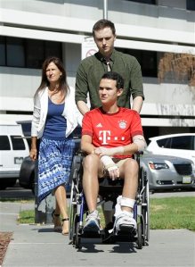 Niall Murray, foreground, is pushed in a wheelchair by his brother Ciarán in front of their mother Helen before speaking at a news conference at Santa Clara Valley Medical Center in San Jose, Friday, Sept. 11, 2015. Murray was one of the Irish college students injured in a balcony collapse in Berkeley, Calif., on June 16, 2015 that killed six others. (AP Photo/Jeff Chiu)