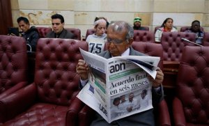 Pedro Osuna Ramirez, 67, who says that he and his family were pushed from their land in central Colombia by rebels of the Revolutionary Armed Forces of Colombia (FARC), reads a newspaper during a hearing with victims of the guerrilla group inside Congress in Bogota, Colombia, Thursday, Sept. 24, 2015. Colombia's president and leaders of the FARC met in Havana on Wednesday, and vowed to end Latin America's longest-running armed conflict in the coming months. The newspaper's headline reads in Spanish "Final agreement in six months." (AP Photo/Fernando Vergara)