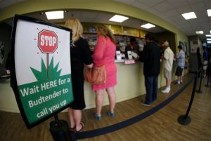 In this photograph taken with a fisheye lens Saturday, April 25, 2015, buyers make their purchases at the counter as a contingent of lawmakers, their staffers and a handful of lobbyists tour one of two retail and grow operations for both medical and recreational marijuana in northeast Denver. Colorado's unusual tax law is forcing the state to suspend taxes on recreational marijuana for one day, Sept. 16, during which a 10 percent sales tax and a 15 percent excise tax will not be collected. (AP Photo/David Zalubowski)