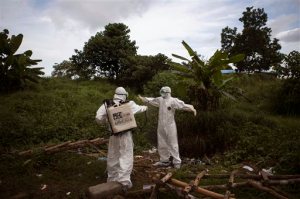 ADVANCE FOR USE SUNDAY, SEPT. 20, 2015 AT 9 P.M. EDT (0100 GMT) AND THEREAFTER - FILE - In this Wednesday, Sept. 24, 2014 file photo, a health worker sprays a colleague with disinfectant after working inside a morgue with people suspected of dying from the Ebola virus, in Kenema, eastern Sierra Leone. An Associated Press investigation has found that the World Health Organization and other responders faced key obstacles in their efforts to stop the spiraling Ebola outbreak in the summer of 2014 in Kenema, a pivotal seeding point for the virus and a microcosm of the messy response across West Africa. (AP Photo/Tanya Bindra, File)