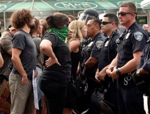 Protesters look through a line of Baltimore City police as Kwame Rose, an activist, is detained by police as protesters rallied outside the Baltimore courthouse during the first court hearing for six Baltimore police officers who are charged in the death of Freddie Gray, a black man who died a week after suffering a critical spine injury in custody. The protesters blocked traffic as they marched to the corner of Calvert and Pratt Streets in the Inner Harbor.  (Kim Hairston/Baltimore Sun via AP) WASHINGTON EXAMINER OUT; MANDATORY CREDIT