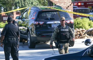 In this Friday, Sept. 18, 2015 photo, law enforcement officers collect evidence and inspect the scene of a vehicle crash and shootout in Tucker, Ga. Officer Marco Vizcarrando, a 19-year veteran of the DeKalb County Police Department, was injured during a shootout with two suspects and has been released from a hospital after being treated for a shoulder injury, authorities said Saturday. (AP Photo/ Ron Harris)