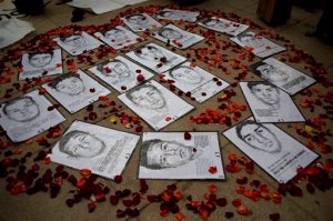 FILE.- In this March 26, 2015 file photo drawings of some of 43 missing students are surrounded by flower petals, formimg the shape of a heart, during a protest marking the six-month anniversary of their disappearance, in Mexico City. An independent report released Sunday Sept. 6, 2015 dismantles the Mexican governments investigation into last years disappearance of 43 teachers college students, starting with the assertion that the giant funeral pyre in which the attorney general said they were burned to ash beyond identification simply never happened.(AP Photo/Rebecca Blackwell, file)