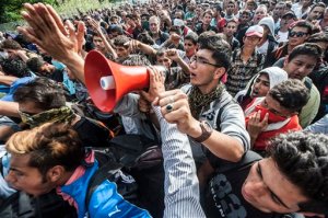 Migrants demonstrate at the "Horgos 2" border crossing into Hungary, near Horgos, Serbia, Wednesday, Sept. 16, 2015. Small groups of migrants continued to sneak into Hungary on Wednesday, a day after the country sealed its border with Serbia and began arresting people trying to breach the razor-wire barrier, while a first group arrived in Croatia seeking another way into the European Union. (Sandor Ujvari/MTI via AP)