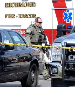 CORRECTS TO GLINIEWICZ FROM GLINIEWITZ- A heavily armed police officer walks in a shopping area after searching for suspects in the shooting of a police officer Tuesday, Sept. 1, 2015 in Fox Lake, Ill. Fox Lake Police Lt. Charles Joseph Gliniewicz was shot and killed while pursuing a group of suspicious men. Police with helicopters, dogs and armed with rifles are conducting a massive manhunt in northern Illinois for the individuals  believed to be involved in the death of the three-decade member of the department and a father of four sons. (AP Photo/Michael Schmidt)