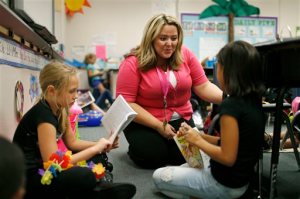 In this Sept. 10, 2015, photo, Tia Martin, center, works with Izabel Martinez, left, and Ashlyn Dowding in a third-grade class at Ulis Elementary School in Henderson, Nev. Martin is a long-term substitute teacher who is taking an alternative route to licensure program to get a regular teaching license. After years of recession-related layoffs and hiring freezes, school systems in pockets across the United States are in urgent need of more qualified teachers, and students, instead of meeting their new teacher on their first day of class, are finding a substitute. (AP Photo/John Locher)