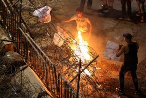 Lebanese anti-government protesters burn garbage on the barbed wire barrier during a protest against the ongoing garbage crises and the government corruption, in front of the government house in downtown Beirut, Lebanon, Wednesday, Sept. 16, 2015. Lebanese police beat back protesters with clubs and sticks and arrested dozens of people in downtown Beirut Wednesday as a second session of dialogue between politicians got underway, the latest confrontations this city has seen over the country's summer trash crisis. (AP Photo/Hussein Malla)