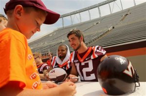Virginia Tech quarterbacks Brenden Motley (9) left, and Michael Brewer (12) sign autographs for visiting Hokie fans including Jet Jones, 8 of Willington N.C. as the Virginia Tech football team held its annual pre-season media and fan appreciation day in Blacksburg, Va., on Saturday, Aug. 15, 2015. Virginia Tech is scheduled to play defending national champion Ohio State in the first game of the season Monday, Sept. 7. (Matt Gentry/The Roanoke Times via AP)