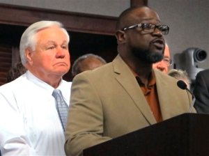 Anthony Scott, the brother of Walter Scott, the unarmed black motorist who was shot and killed by a North Charleston, S.C., police officer earlier this year, speaks Thursday, Oct. 8, 2015, in North Charleston after the city council approved a $6.5 million settlement with the Scott family. North Charleston Mayor Keith Summey is at left. (AP Photo/Bruce Smith)