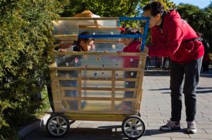 A child stares at another who is placed inside his home made stroller at a park in Beijing, China, Friday, Oct. 30, 2015.  Shares of companies making diapers, baby strollers and infant formula were getting a boost Friday from China's decision to scrap its decades-old one-child policy. (AP Photo/Ng Han Guan)