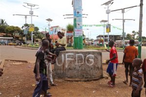 People walk in the street past painting on a structure, center, in support of Guinean opposition presidential candidate Cellou Dalein Diallo, of the UFDG party in Conakry, Guinea, Saturday, Oct. 17, 2015, Guinea President Alpha Conde is far ahead of his closest competitor in his bid for re-election and could garner enough support to avoid a runoff, according to preliminary results available Saturday. (AP Photo/Youssouf Bah)