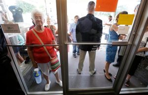 FILE - In this Sept. 6, 2015, file photo, a local resident looks through the front door of Uncle Nancy's Coffee House as Democratic presidential candidate Hillary Rodham Clinton speaks during a campaign stop in Newton, Iowa. The Associated Press interviewed nearly 70 Democratic and independent voters in the past two weeks, all at places where Clinton has campaigned in the first-to-vote primary states of Iowa and New Hampshire. Those voters expressed a litany of concerns with Clinton and her candidacy. (AP Photo/Charlie Neibergall, File)