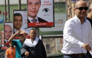 Egyptians walk in front of posters of parliamentary candidates, in Giza, near Cairo, Egypt, Wednesday, Oct. 14, 2015. Egypt's long-awaited parliamentary elections will start on Oct. 18-19, a hoped-for step toward democracy amid a harsh crackdown on dissent. The second stage of the staggered vote will take place on Nov. 22-23. Final results will be announced in early December. (AP Photo/Amr Nabil)