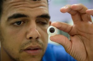 In this Tuesday, Oct. 6, 2015, photo, Mohammed el-Eshra, who lost his left eye in an accident when he was child, looks at artificial eye at Al-Radwan Clinic in Gaza City. Established in 2013, the center assists those who lost an eye to an illness, congenital defects or injury, including those in conflicts. Al-Radwan is the only company in Gaza to design and fit artificial eyes. (AP Photo/Adel Hana)