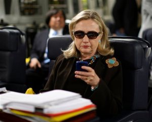 FILE - In this Oct. 18, 2011, file photo, then-Secretary of State Hillary Rodham Clinton checks her Blackberry from a desk inside a C-17 military plane upon her departure from Malta, in the Mediterranean Sea, bound for Tripoli, Libya. The private email server running in Clintons home basement when she was secretary of state was connected to the Internet in ways that made it more vulnerable to hackers, according to data and documents reviewed by The Associated Press. (Kevin Lamarque/Pool Photo via AP, File)