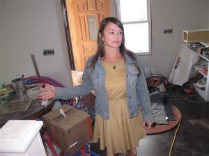 In this Oct. 22, 2015 photo, Krista Sperber examines the living room of her newly rebuilt home in Belmar, N.J., shortly before the third anniversary of Superstorm Sandy. Belmar started a fundraising drive that brought in around $240,000 in cash and materials for Sperber and another woman whose home was wrecked in the 2012 storm to finally move back home. (AP Photo/Wayne Parry)