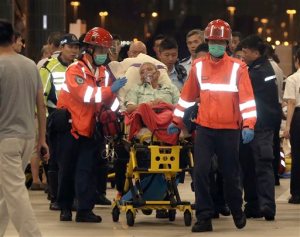 An injured passenger of a high-speed ferry is escorted by rescuers to a hospital after getting on shore in Hong Kong Monday, Oct. 26, 2015. More than 120 people were injured when the ferry traveling from the Asian gambling hub of Macau to Hong Kong slammed into an object floating in the water, authorities said Monday. (Apple Daily via AP) HONG KONG OUT, TAIWAN OUT