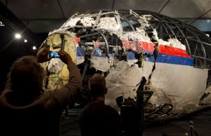 Journalists take images of part of the reconstructed forward section of the fuselage after the presentation of the Dutch Safety Board's final report into what caused Malaysia Airlines Flight 17 to break up high over Eastern Ukraine last year, killing all 298 people on board, during a press conference in Gilze-Rijen, central Netherlands, Tuesday, Oct. 13, 2015. (AP Photo/Peter Dejong)