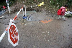 A child walks past a checkpoint on the Serbian side of the border toward Croatia near the  village of Berkasovo, near Sid, Serbia, on Thursday, Oct. 15, 2015. The migrants and refugees are struggling with the autumn rain and the cold as EU leaders are discussing in Brussels how to deal with the crisis. (AP Photo/Amel Emric)