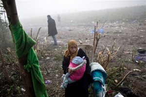 A woman holds a child as she waits to cross from Serbia into Croatia, in Berkasovo, Serbia, Friday, Oct. 23, 2015. Most migrants fleeing war and poverty in the Middle East, Asia and Africa wish to go to Germany or other wealthier countries of Western Europe. (AP Photo/Marko Drobnjakovic)