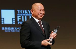 Hong Kong director John Woo smiles during the awarding ceremony of Samurai Award at the 28th Tokyo International Film Festival in Tokyo Monday, Oct. 26, 2015. "I have to say that I'm very surprised. I never thought that I would receive this award. Even though I have made a lot of films but it hardly qualifies as making a special contribution (to cinema). I'm just a hard working film maker. I'm very thankful to receive this award and also very surprised.," Woo said. The award was launched to honor trailblazers in cinema who have made outstanding contributions to the art of movie making. (AP Photo/Shizuo Kambayashi)