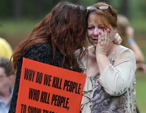 Dawn Skorcik, left, of Marietta, Ga., and Dawn Barber, of Powder Springs, Ga., comfort each other while protesting outside of Georgia Diagnostic Prison in Jackson, Ga., Tuesday evening, Sept. 29, 2015, before the execution of Kelly Gissendaner. Gissendaner was convicted of murder in the February 1997 slaying of her husband. She conspired with her lover, who stabbed Douglas Gissendaner to death. She is scheduled to die by lethal injection Tuesday night. (Ben Gray/Atlanta Journal-Constitution via AP)  MARIETTA DAILY OUT; GWINNETT DAILY POST OUT; LOCAL TELEVISION OUT; WXIA-TV OUT; WGCL-TV OUT; MANDATORY CREDIT