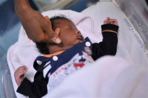 In this picture taken on Sept. 17, 2015, 24-year-old Ester Terry, from Nigeria, caresses her son Khalifa Nyka at Catania's Cannizzaro hospital, Italy. Ester Terry was just about to deliver her baby when the Italian Coast Guard rescued her in the Mediterranean Sea: she managed to safely give birth to a male child, with the help of a doctor aboard the Italian vessel while still at sea on the way to Lampedusa, the Southernmost European island. (AP Photo/Salvatore Cavalli)