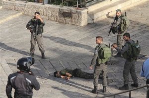 Israeli police stand around a Palestinian shot after he allegedly tried to stab a person at Damascus Gate of the Jerusalem's Old City, Wednesday, Oct. 14, 2015, Israeli police said. (AP Photo/Oren Ziv)