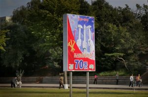 In this Sept. 15, 2015, photo, people walk past a sign board marking the upcoming 70th anniversary of the founding of North Korea's Workers' Party in Pyongyang, North Korea. While North Korea prepares a big show to mark the 70th anniversary of the ruling Workers Party, the daily struggles of life outside the capital - such as finding clean running water and putting nutritious food on the table year-round - pose a harsh, but largely unseen, contrast to the grand celebrations the world will see Oct. 10. (AP Photo/Wong Maye-E)