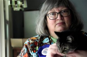 In this photo taken Tuesday, Oct. 20, 2015 gun-control activist Kim Yaman is seen with one her cats in her Cary, N.C. home. Yaman and her children survived a mass shooting at a university in 1991, and she became active in gun-control efforts after the Newtown shooting. (AP Photo/Gerry Broome)