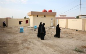 In this Wednesday, Oct. 14, 2015 photo, women walk over the courtyard of a mosque outside the city of Kirkuk, Iraq where they temporarily reside, where over 500 elderly pilgrims are stuck after returning from the hajj.  The Iraqi government permitted only those above age 60 to exit militant territory, escorting them by bus to Baghdad, where they then flew to Mecca. But nearly two months later, the Mosuli hajjaj, as they are known in Arabic, are desperately trying to get home _ blocked by Iraqi and Kurdish authorities near the northern city of Kirkuk who refuse to open a corridor back into militant-held territory.(AP Photo/Bram Janssen)